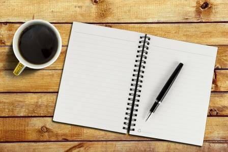 Notebook with pen and cup with coffee on wood table background, close-up